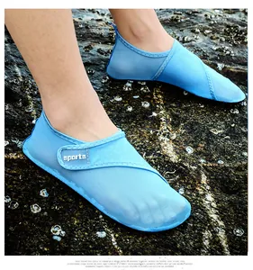 Close-up of light blue breathable aqua shoes worn on wet rocky beach surface