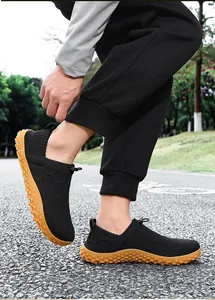 Side view of black mesh wide-toe walking shoes worn by a model during outdoor hiking
