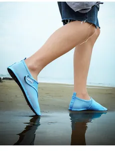 Detailed view of blue quick-dry breathable water shoes being worn on a scenic sandy beach shore