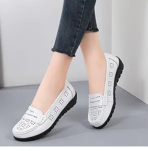 Close-up of white perforated loafers for women with floral cut-outs and black rubber sole.