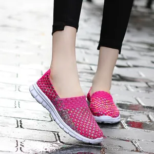 Detailed view of pink breathable elastic woven slip-on shoes worn on a city street.
