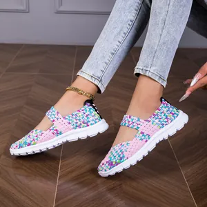 Detail view of lightweight colorful woven elastic flat sandals for women on wood floor.