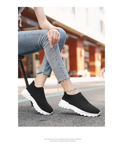 Detailopname van zwarte ademende fly-knit sneakers met witte EVA-zolen op een stadsstraat