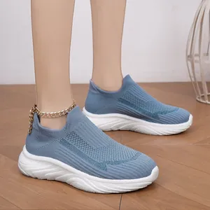 Close-up detail of blue breathable knit slip-on sneakers on feet with white sole