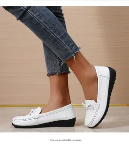 Close-up van comfortabele witte leren loafers met zwarte rubberen zolen en strikdetails.
