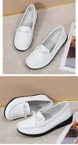 Detailopname van witte leren verpleegsterschoenen met strikje en platte rubberen zool.