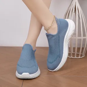 Detail view of blue breathable knit slip-on sock sneakers worn on a wooden floor