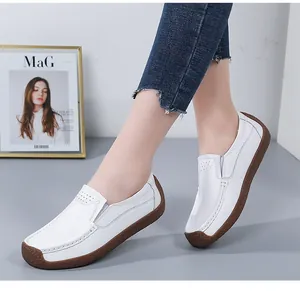 Detail view of white leather flat loafers with textured finish and durable rubber sole.