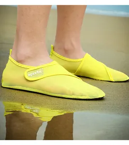 Detail of yellow mesh water shoes on a sandy beach showing the breathable fabric