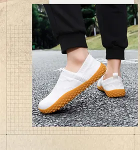 Detailed side view of white breathable fly-knit slip-on sneakers for men outdoors.
