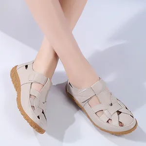Detailansicht der beigen flachen Sandalen mit modischem Ausschnitt am Modellfuß