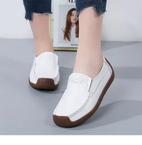 Close-up of comfortable white leather loafers for women with textured brown rubber soles.