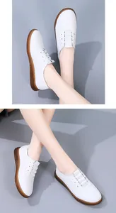 Close-up detail of women's white leather loafers with flexible brown rubber soles.