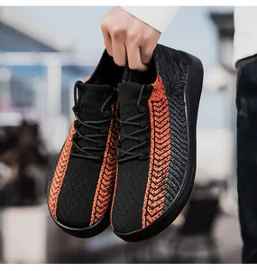 Mano che tiene sneaker a piedi nudi in maglia nera e arancione, dettaglio traspirante.