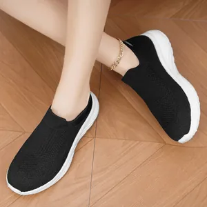 Detailed view of breathable black knit slip-on sneakers featuring flexible white soles