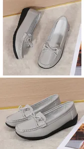 Gedetailleerd overzicht van grijze loafers met witte stiksels en een leuk strikje.