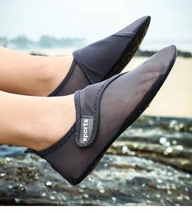 Close-up of breathable grey mesh beach shoes worn on a rocky shore.