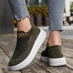 Detailed macro view of olive green breathable flyknit slip-on sneakers on wood