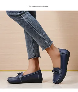 Detailweergave van marineblauwe damesloafers met witte stiksels en een strikaccent