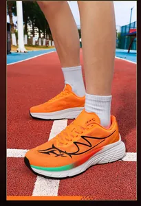 Close-up of bright orange mesh running shoes worn by a model on a red athletic track.