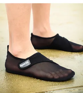 Detailed view of breathable black mesh water shoes on a wet sandy beach background.