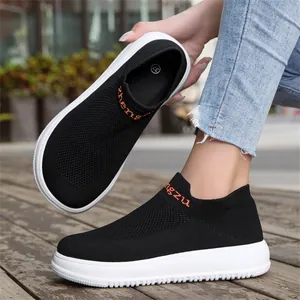 Close-up of black breathable flyknit slip-on sneakers with thick white soles