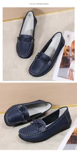 Detailopname van donkerblauwe platte loafers met witte stiksels en een decoratieve strik