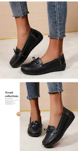 Gedetailleerde weergave van zwarte damesloafers met strikdecoratie en contraststiksels