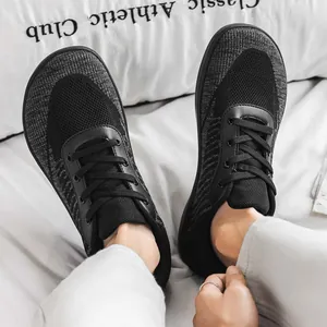 Close-up view of breathable black fly-knit barefoot shoes with a wide toe box design.