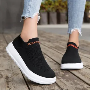 Detailed shot of breathable black fly-knit slip-on sneakers with white soles
