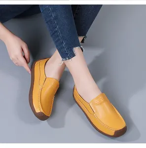 Detail view of yellow leather loafers with brown soles and hand-stitched accents