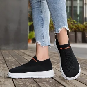 Detail shot of breathable black knit slip-on sneakers with flexible white sole.