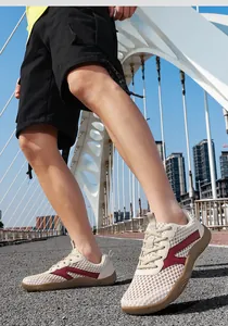 Low angle shot of beige breathable mesh outdoor sneakers worn on an asphalt path.