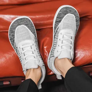 Top view detail of white and grey knit barefoot shoes with wide toe box on a red background
