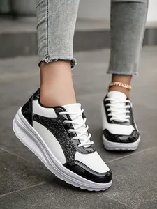 Close-up detail view of women's black and white sequin sneakers paired with denim jeans outdoors