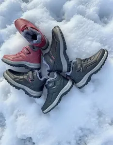 Group of fur-lined winter snow boots for seniors presented on natural snow background