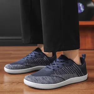 Detail view of breathable navy blue fly-knit wide-toe barefoot casual shoes on model's feet