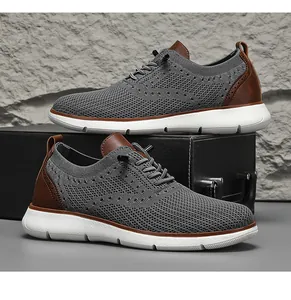 Detailed view of grey breathable fly-knit men's casual shoes with brown leather accents.