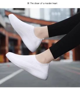 Detail shot of white breathable fly-knit slip-on walking shoes worn in an urban setting