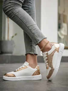 Detailed view of women white sneakers featuring shiny gold sequins and metallic accents