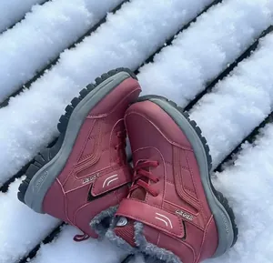 Detailed view of warm burgundy winter snow boots with faux-fur lining on snowy steps