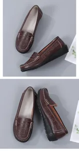 Detailed view of brown perforated leather loafers with white contrast stitching