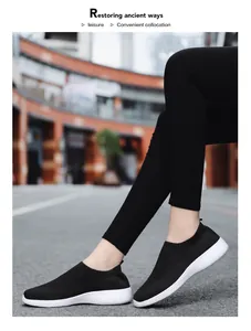Close-up side view of black breathable fly-knit slip-on walking shoes worn outdoors in the street