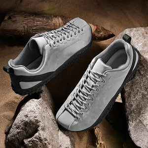 Vue détaillée de chaussures de randonnée grises à bout large sur rochers et sable.