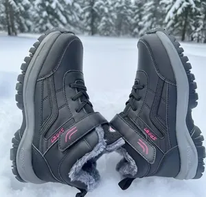 Pair of black waterproof winter snow boots with warm faux fur lining resting on snow