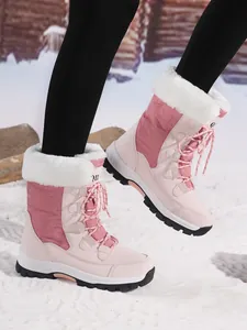 Close-up of pink women's snow boots with white faux fur in a winter snow setting