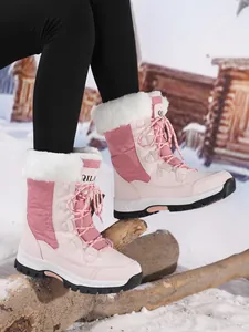 Close-up of pink outdoor snow boots with white faux fur trim on a snowy log.