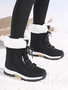 Detailed view of women's black outdoor snow boots with white faux fur lining on snow