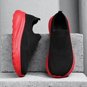 Close-up of breathable black knit slip-on sneakers with vibrant red outsoles