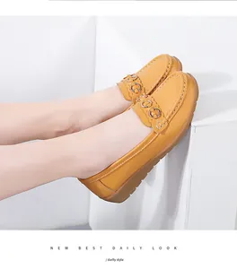 Gedetailleerd overzicht van gele lederen loafers met decoratieve metalen gesp aan de voeten van model